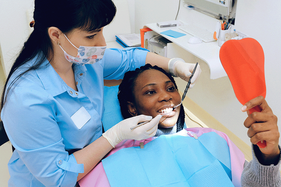 A dentist and a happy patient with a mirror looking at her teeth